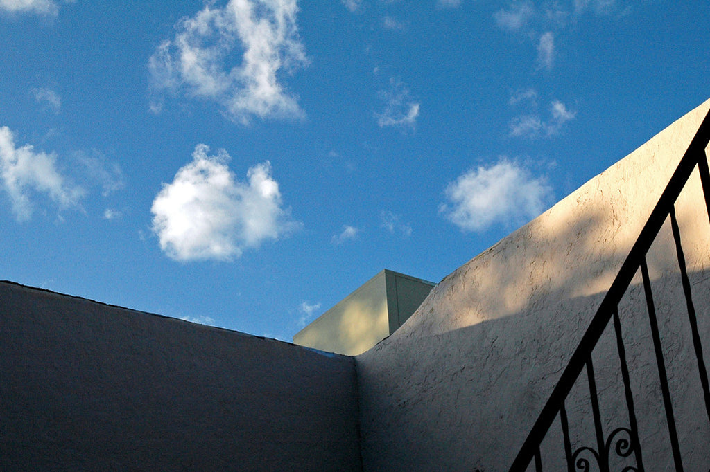 "Blue Sky" ~ Looking up at the side of an adobe house at bright blue sky with white clouds.