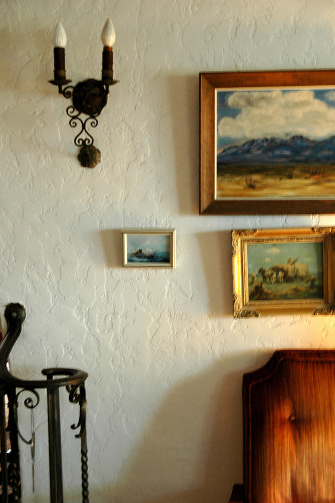 "El Paso Sky" ~ A section of a living room with paintings and a wall sconce. Photo by Ann Woodall